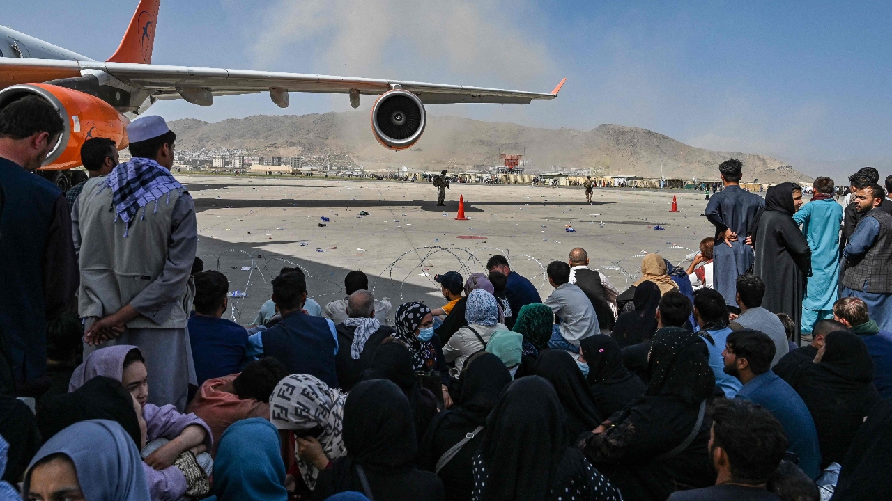 Afghan people sit as they wait to leave the Kabul airport. Credit: AFP Photo