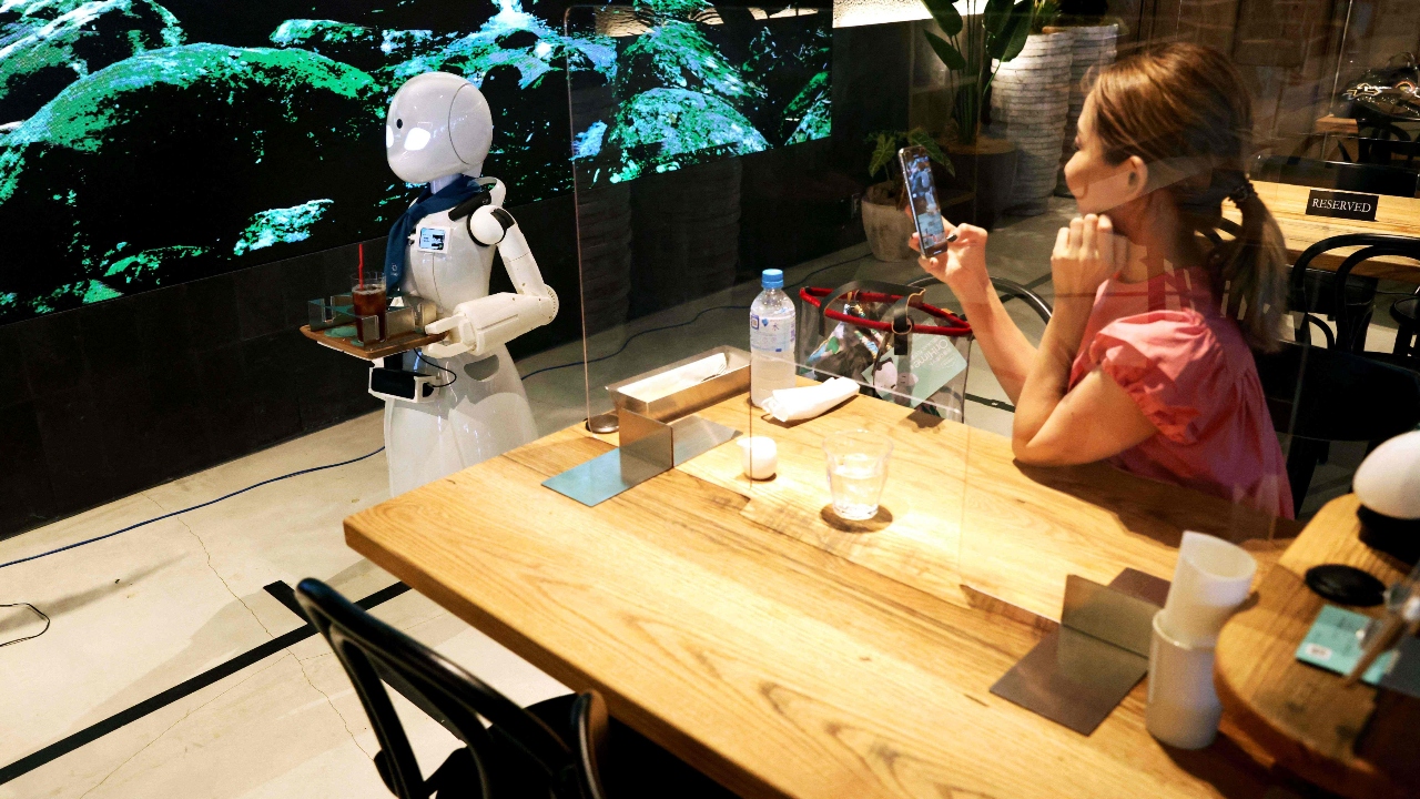 A customer takes pictures of a humanoid robot delivering drinks at the Dawn Cafe in Tokyo. Credit: AFP Photo