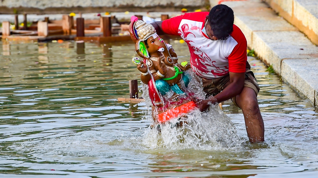 A volunteer immerses an idol of Lord Ganesh at Ulsoor lake in Bengaluru. Credit: PTI Photo