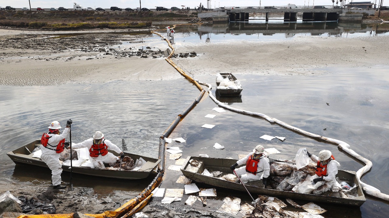 Workers in protective suits clean oil in the area of the Talbert Marsh wetlands after a 126,000-gallon oil spill from an offshore oil platform in Huntington Beach, California. Credit: AFP Photo