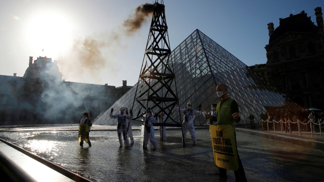 Greenpeace activists stand next to an oil drilling rig replica in front of the glass pyramid of the Louvre museum during a protest in Paris. Credit: Reuters Photo