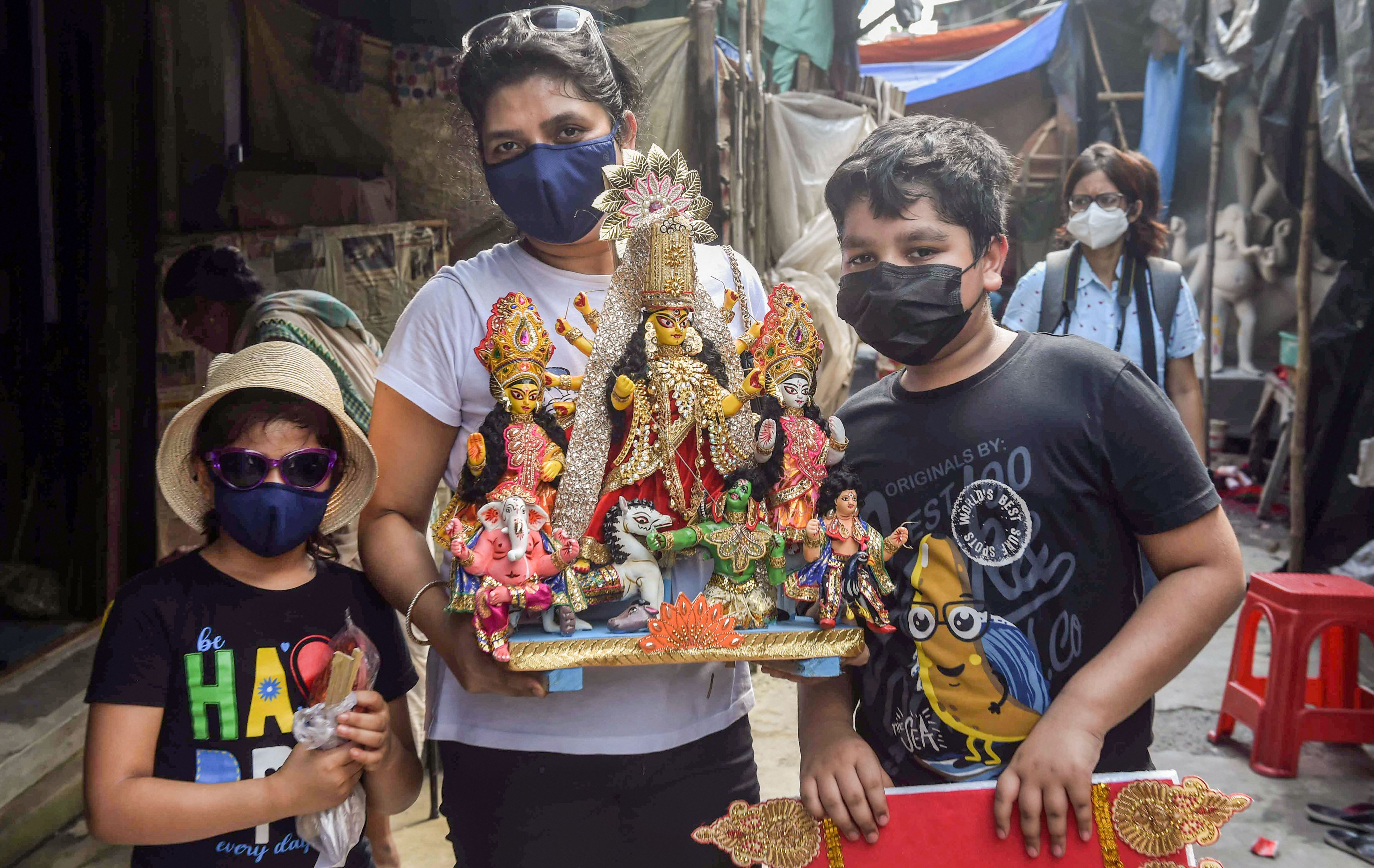 A woman with children carry an idol of Goddess Durga ahead of Durga Puja festival at Kumartuli in Kolkata. Credit: PTI Photo
