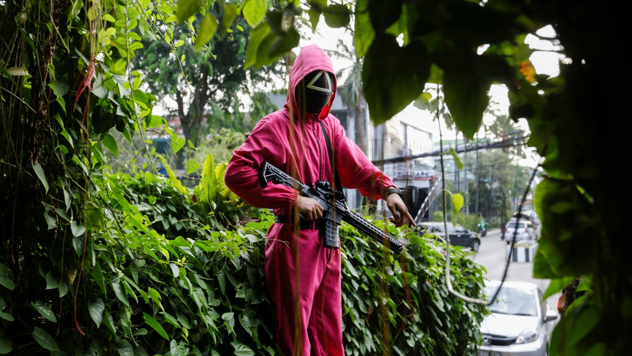A staff member wearing 'Squid Game' costume gestures as he stands guard at Strawberry Cafe in Jakarta, Indonesia. Credit: Reuters Photo