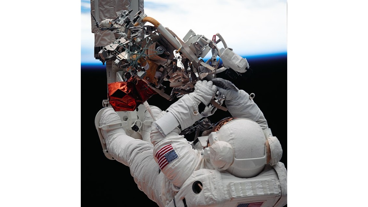 Franklin Story Musgrave is seen in the space suit working on HST at the age of 61. Credit: Wikimedia Commons