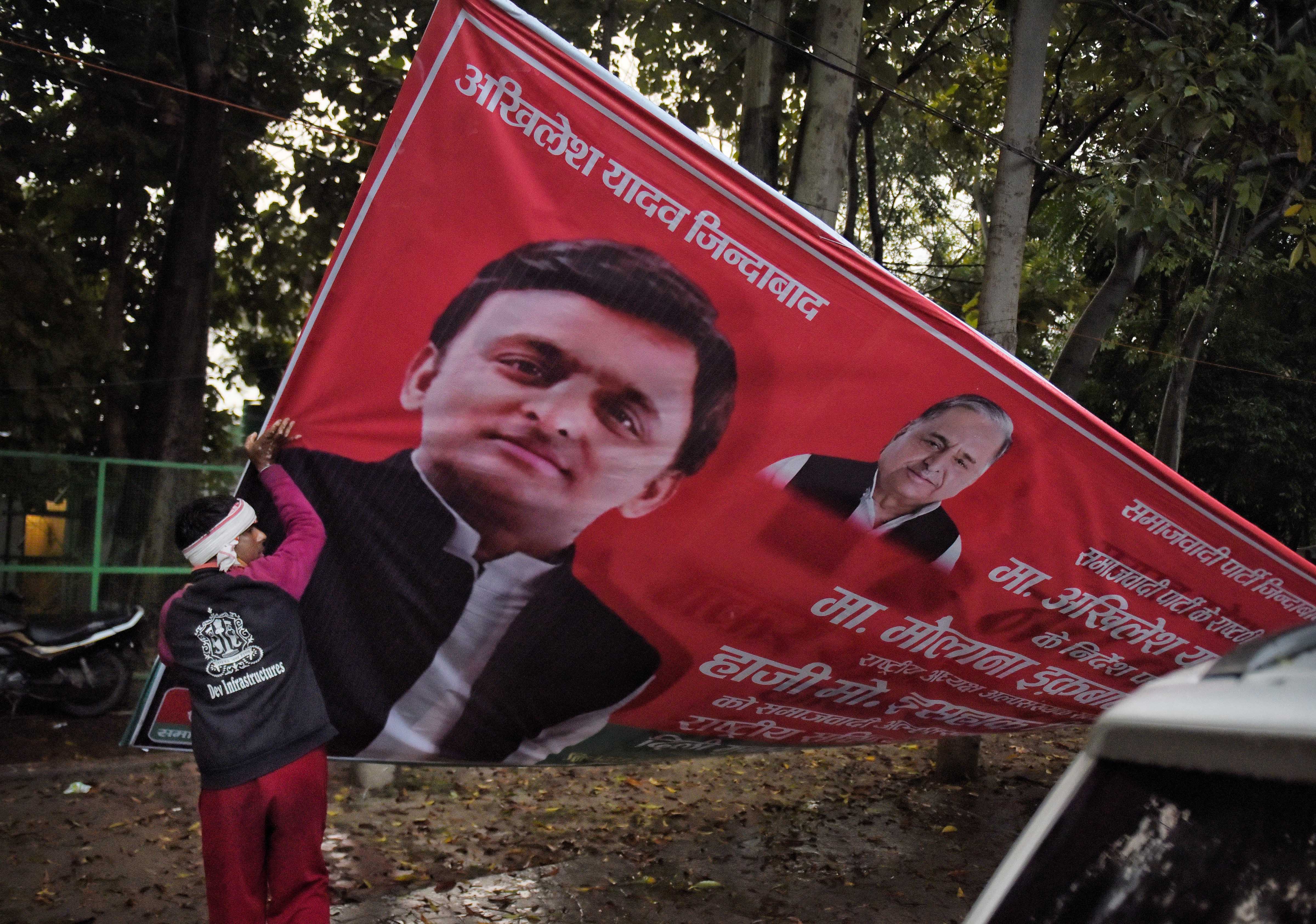 A UP administration worker removes a political banner as the Model Code of Conduct has come into effect after the announcement of the schedule of UP Assembly elections. Credit: PTI Photo