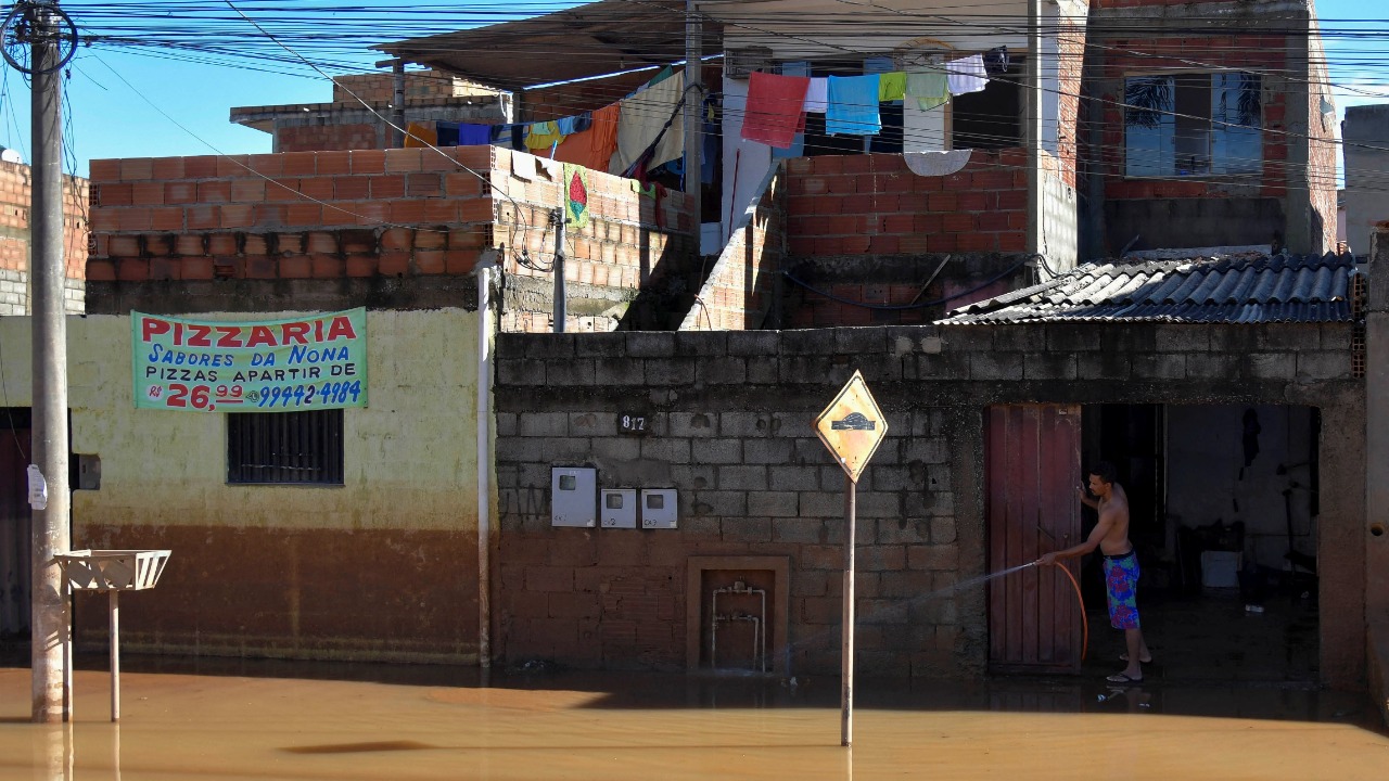 A resident uses a hose at a flooded area after pouring rains in Mario Campos, in Minas Gerais state, Brazil. Credit: Reuters Photo