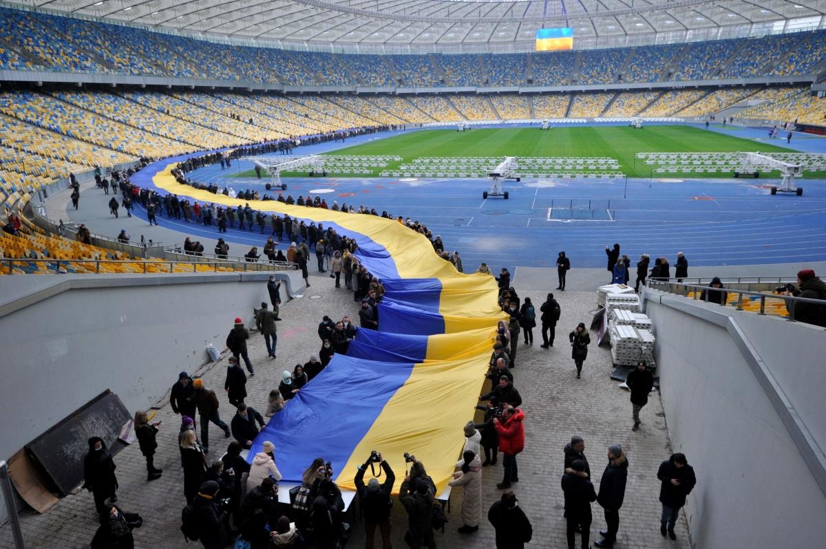 People carry a giant Ukraine's national flag at a stadium to mark a