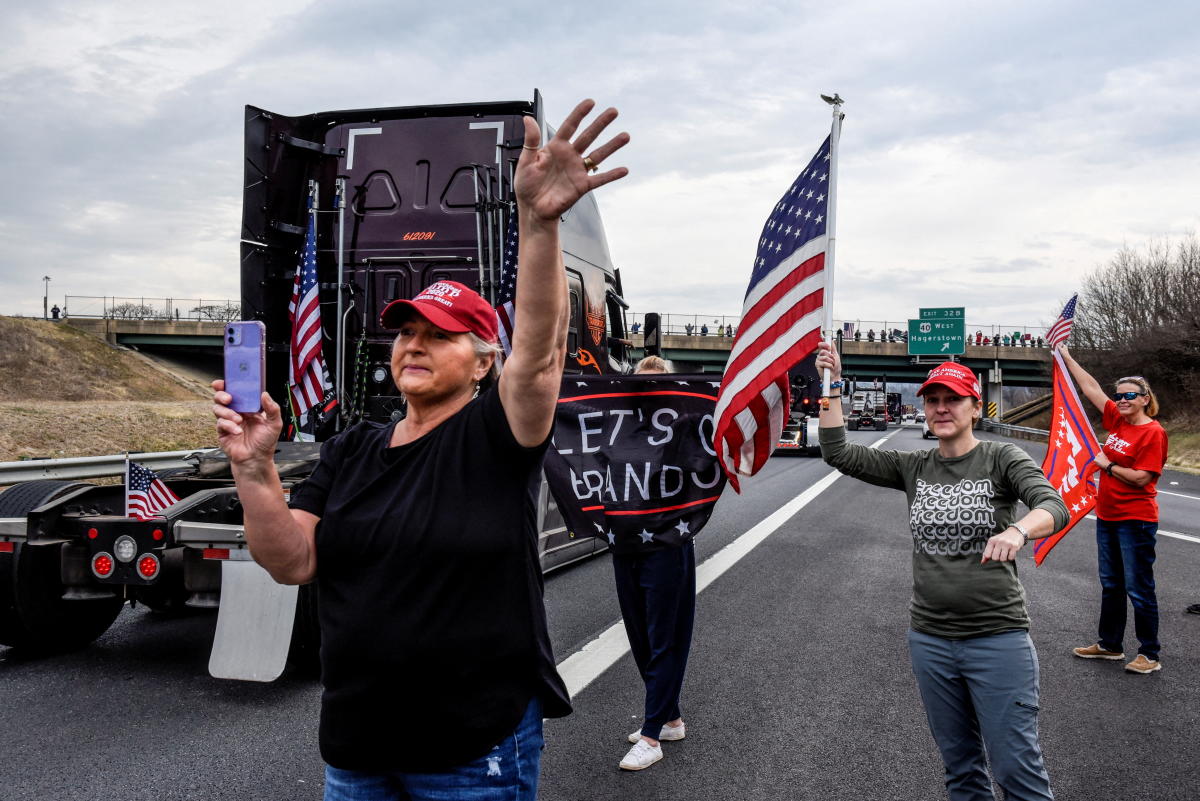 People cheer as hundreds of vehicles including 18-wheeler trucks, RVs and other cars drive towards Washington D.C. after some of them arrived as part of a convoy that traveled across the country to protest COVID-19 related mandates and other issues in Hagerstown, Maryland, US. Credit: Reuters Photo