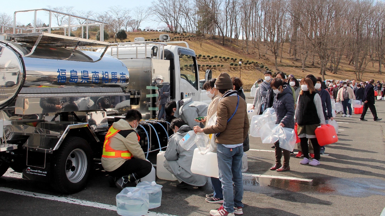 Residents queue to fill containers with water from a tanker truck in Minamisoma, Fukushima prefecture on March 17, 2022, after the water was cut off following a 7.3-magnitude quake that jolted east Japan the night before. Credit: AFP Photo