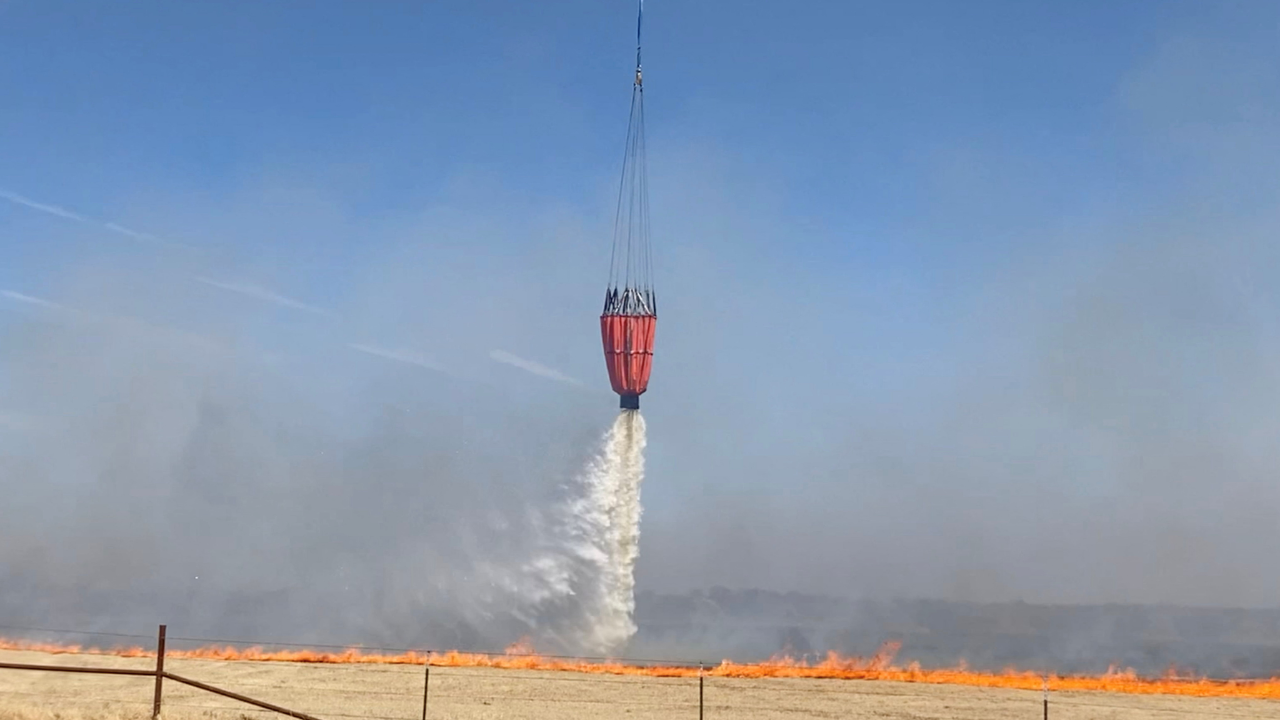 A helicopter unloads water onto a burning field as crews battle the Eastland Complex Fire in Eastland County, Texas, US. Credit: Reuters Photo