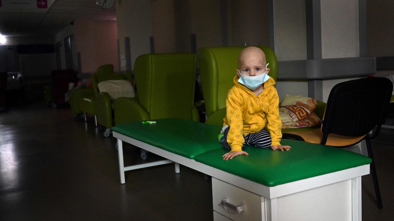 A little patient stands on a medical bench in the basement of Kyiv's central children's hospital, prior to the evacuation from the hospital to Poland and Germany, in Kyiv. Credit: AFP Photo