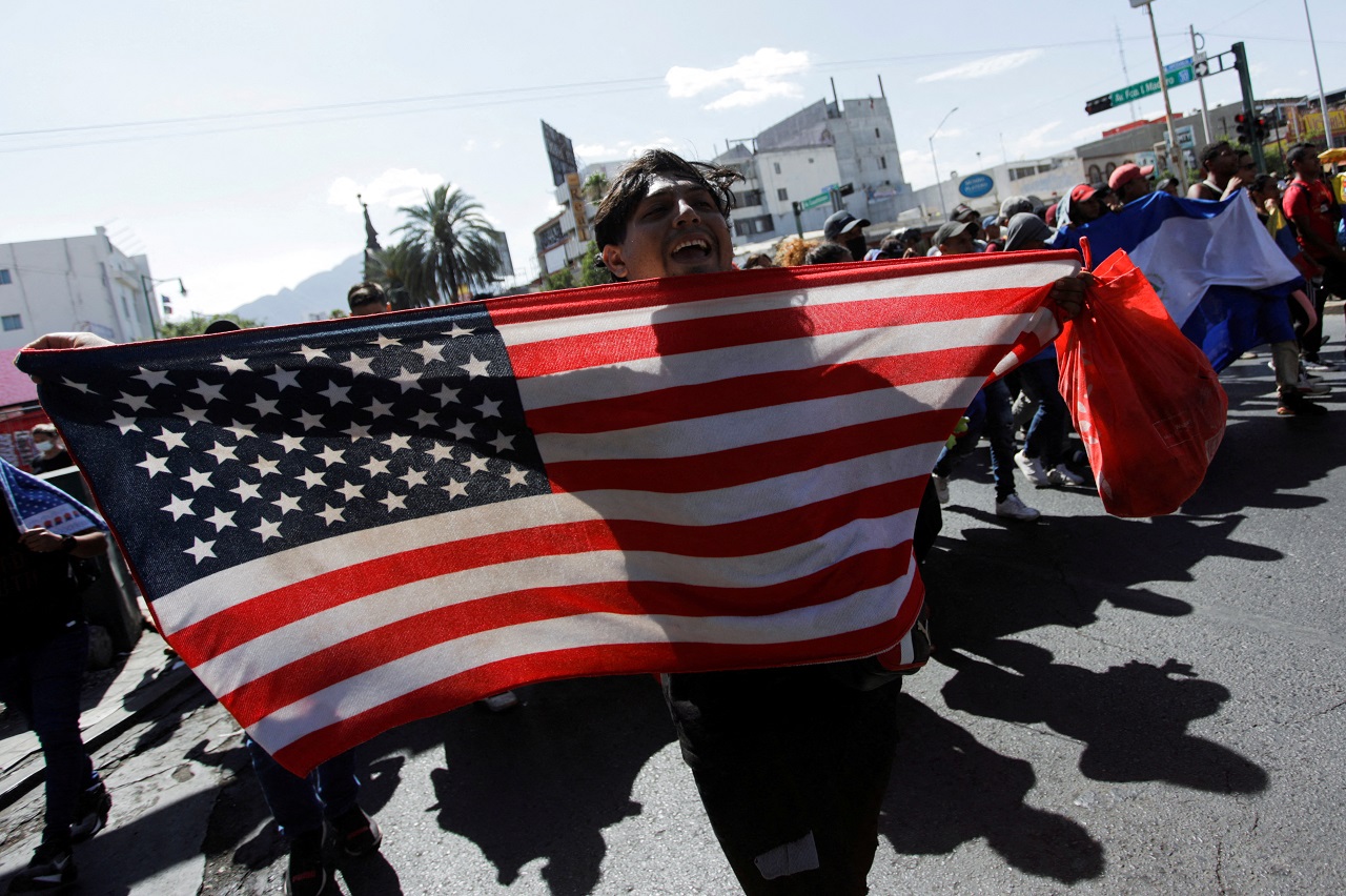 A migrant reacts as he holds a U.S. flag during a protest after being denied tickets at the bus station to travel to Ciudad Acuna in an attempt to cross the border to Del Rio, Texas, US, in Monterrey. Credit: Reuters Photo