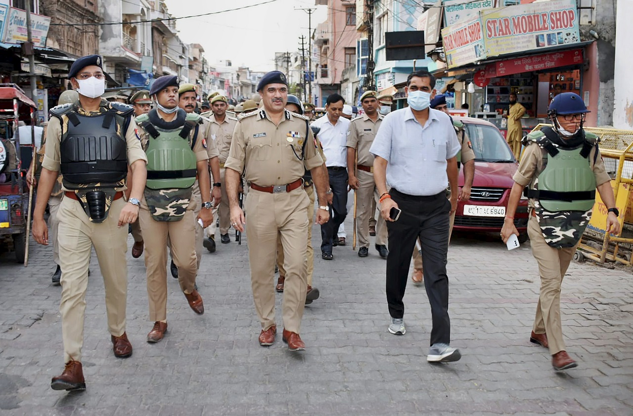 Meerut zone ADG Rajeev Sabharwal (C), Bulandshahr SSP Shlok Kumar(R) and Bulandshahr District Magistrate Chandra Prakash Singh with police personnel conduct a route march to maintain law and order in the city. Credit: PTI Photo