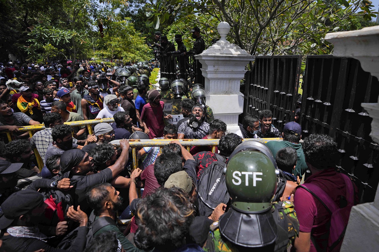 Protesters use an iron barricade to break the gate as they storm the compound of Sri Lankan Prime Minister Ranil Wickremesinghe's office. Credit: AP Photo