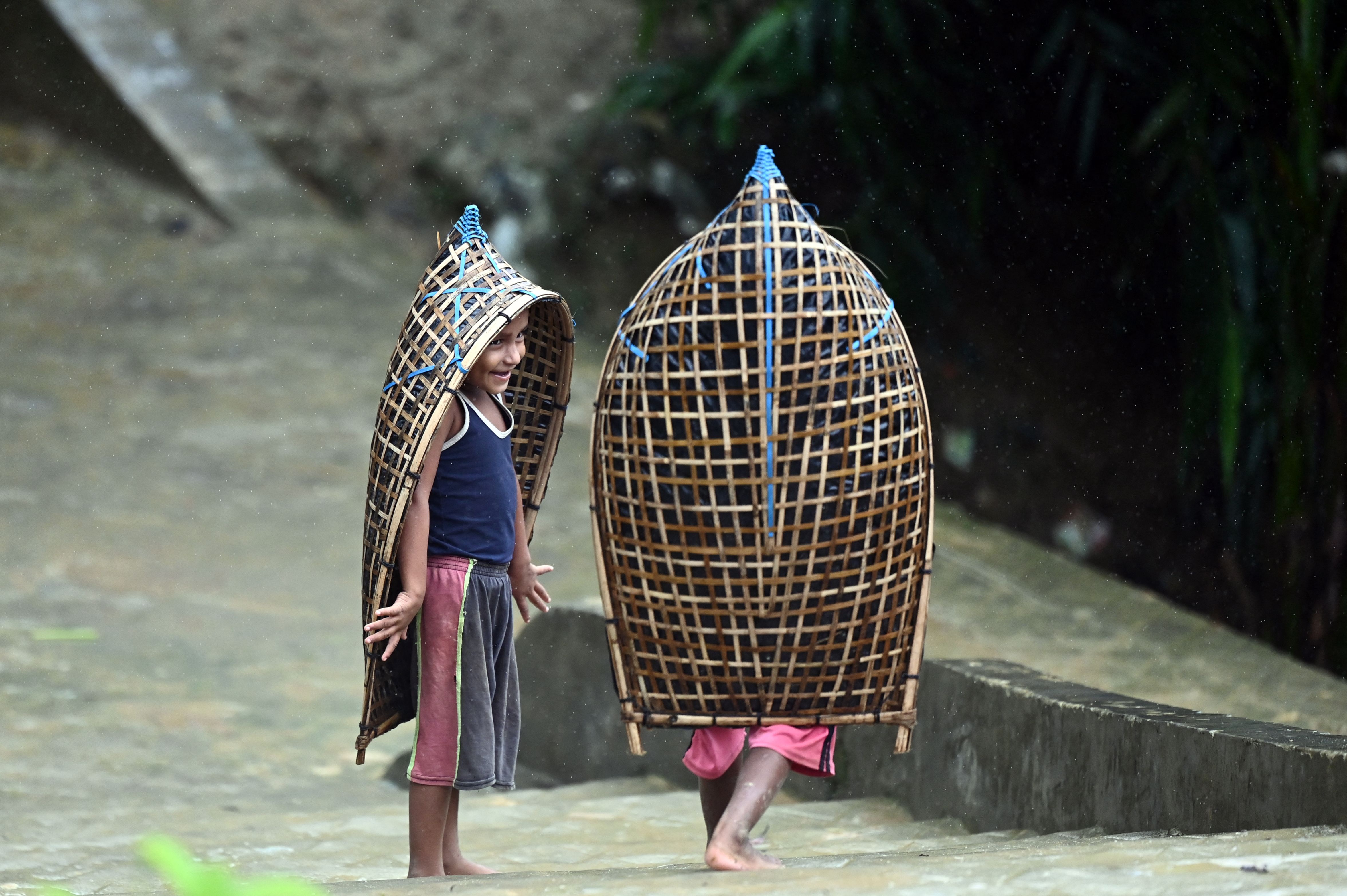 Rohingya refugee children gesture as they make their way during monsoon rainfall in Kutupalong refugee camp in Ukhia. Credit: AFP Photo
