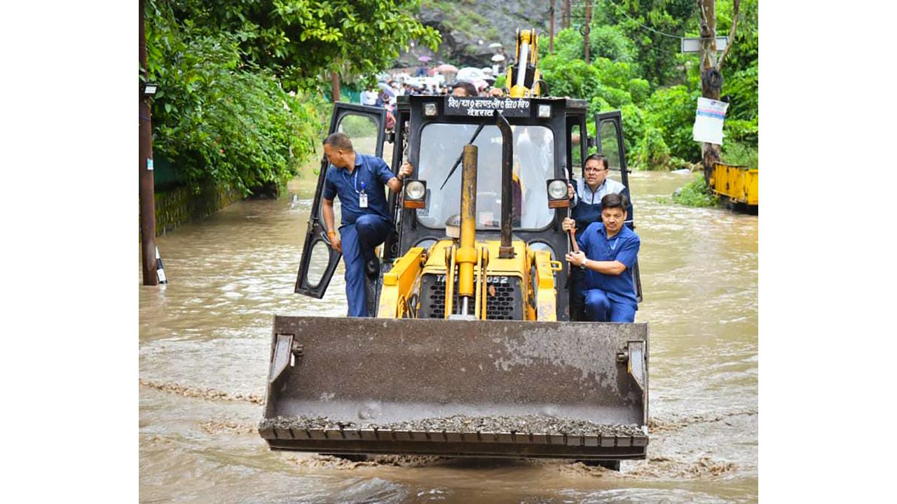 CM Dhami aboard an earthmover visits the affected areas after a cloudburst in Dehradun. Credit: UKCMO
