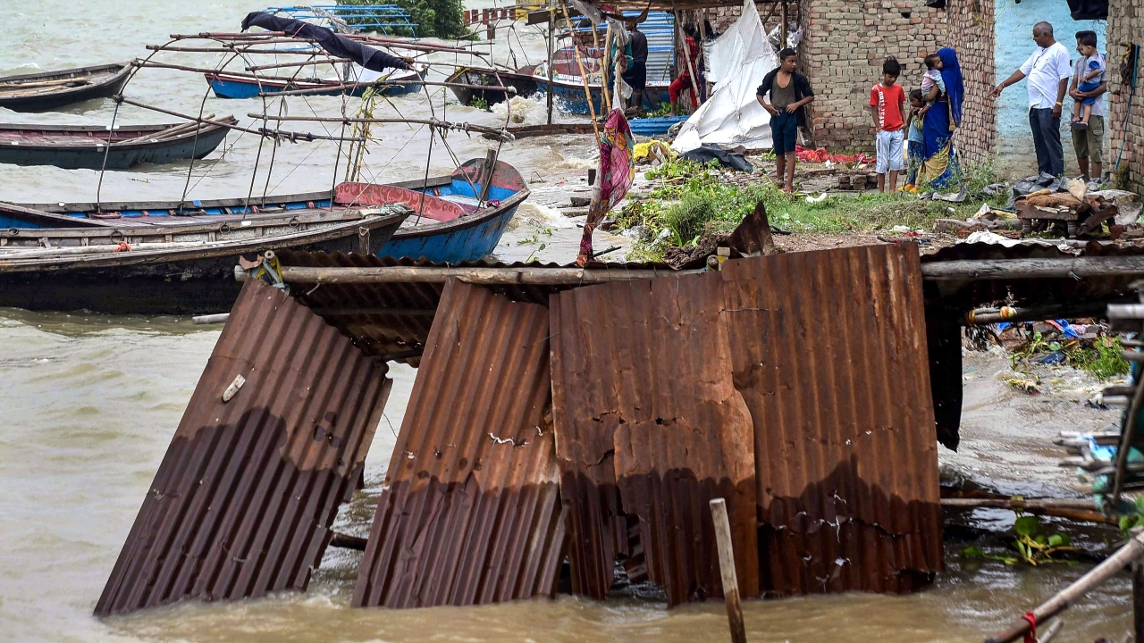Residents at a flooded area watch the water rise following monsoon rains, in Prayagraj. Credit: PTI Photo