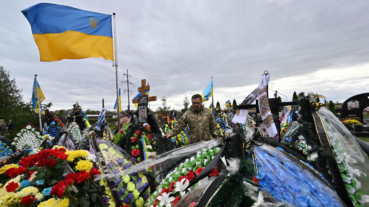 A Ukrainian officer reacts near a grave at the Heroes Alley of the cemetery of Bucha, Kyiv region on October 3, 2022, amid the Russian invasion of Ukraine. Credit: AFP Photo