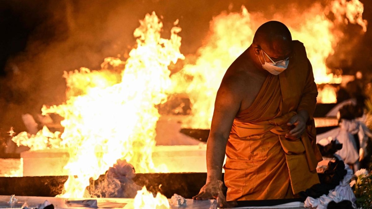 A monk touches the coffin of a victim of the nursery mass shooting during the cremation ceremony in Na Klang in northeastern Nong Bua Lam Phu province on October 11, 2022. Credit: AFP Photo