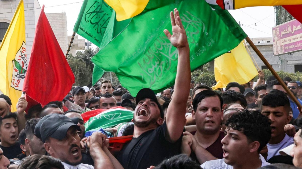 Mourners carry the body of Usama Adawi, 18, killed a day earlier during clashes between Palestinians and Israeli security forces, during his funeral in Al-Aroub refugee camp, north of the occupied West Bank city of Hebron, on October 13,2022. Credit: AFP Photo