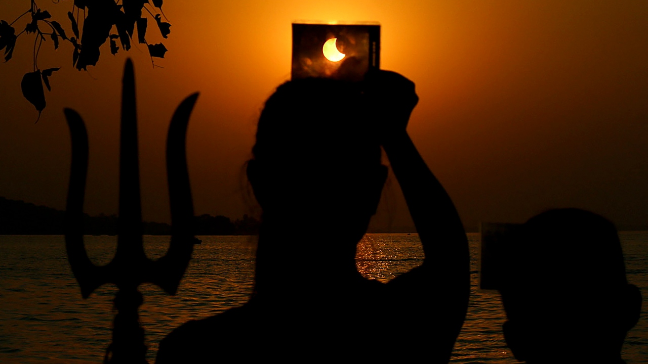 A woman watches the solar eclipse through a strip of exposed X-ray film in Bhopal. Credit: PTI Photo