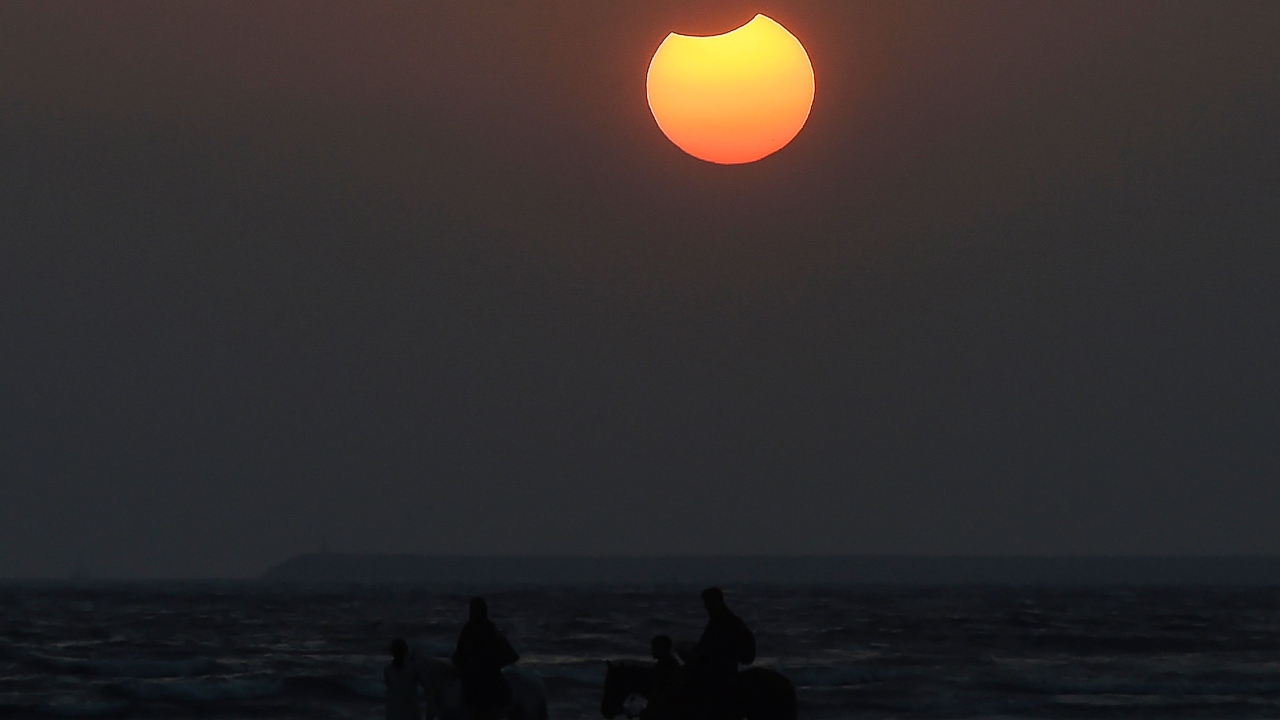 People watch a solar eclipse at a beach in Karachi, Pakistan. Credit: AFP Photo