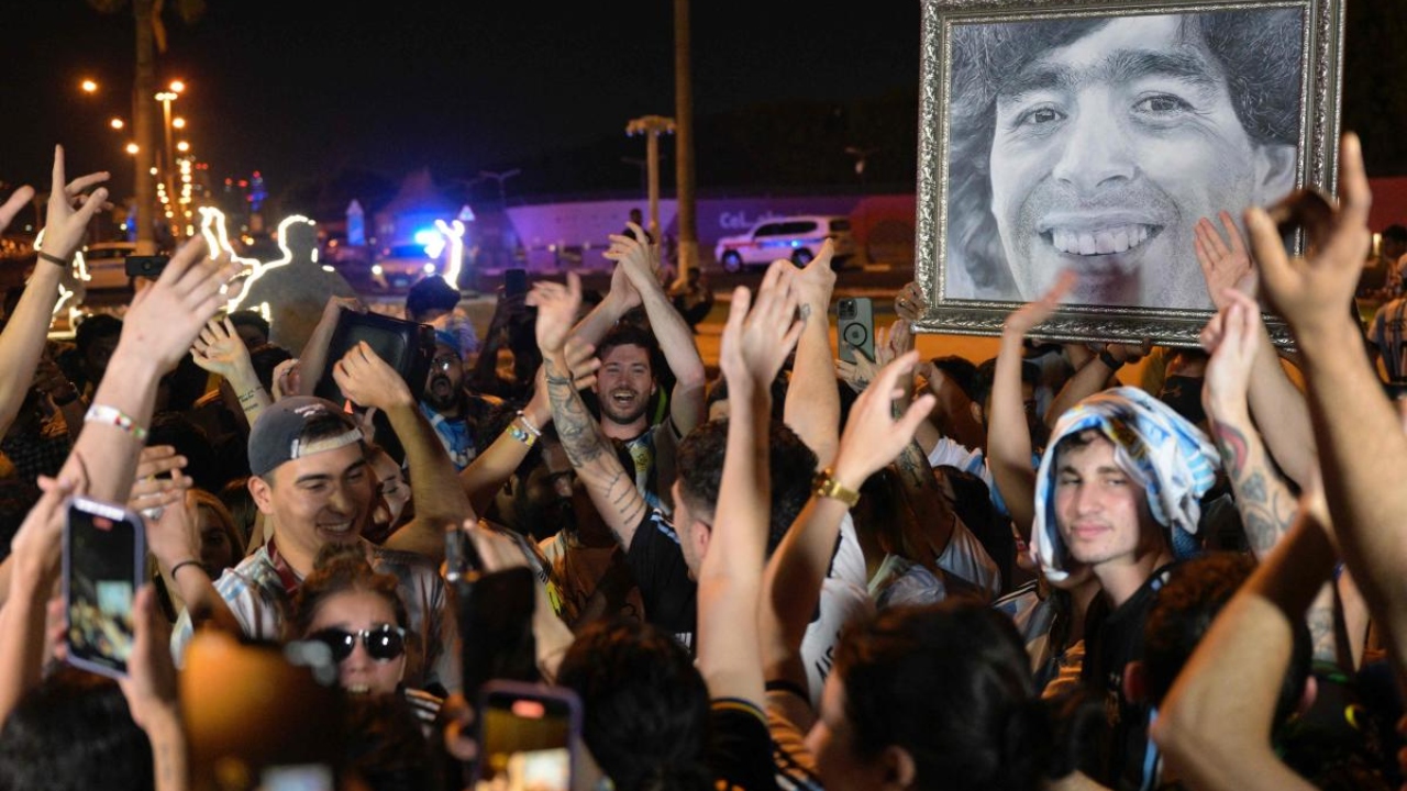 Argentine fans hold up a portrait of late football star Diego Maradona while waiting for the arrival of Argentina’s football team outside of their base camp in Doha on November 17, 2022 ahead of the FIFA World Cup Qatar 2022. Credit: AFP Photo