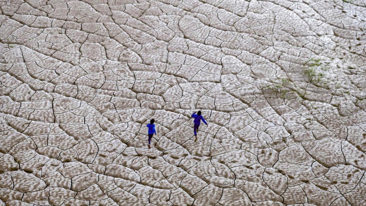 Boys run along the dried-up portion of a riverbed on the banks of river Ganges in Prayagraj, on November 17, 2022. Credit: AFP Photo