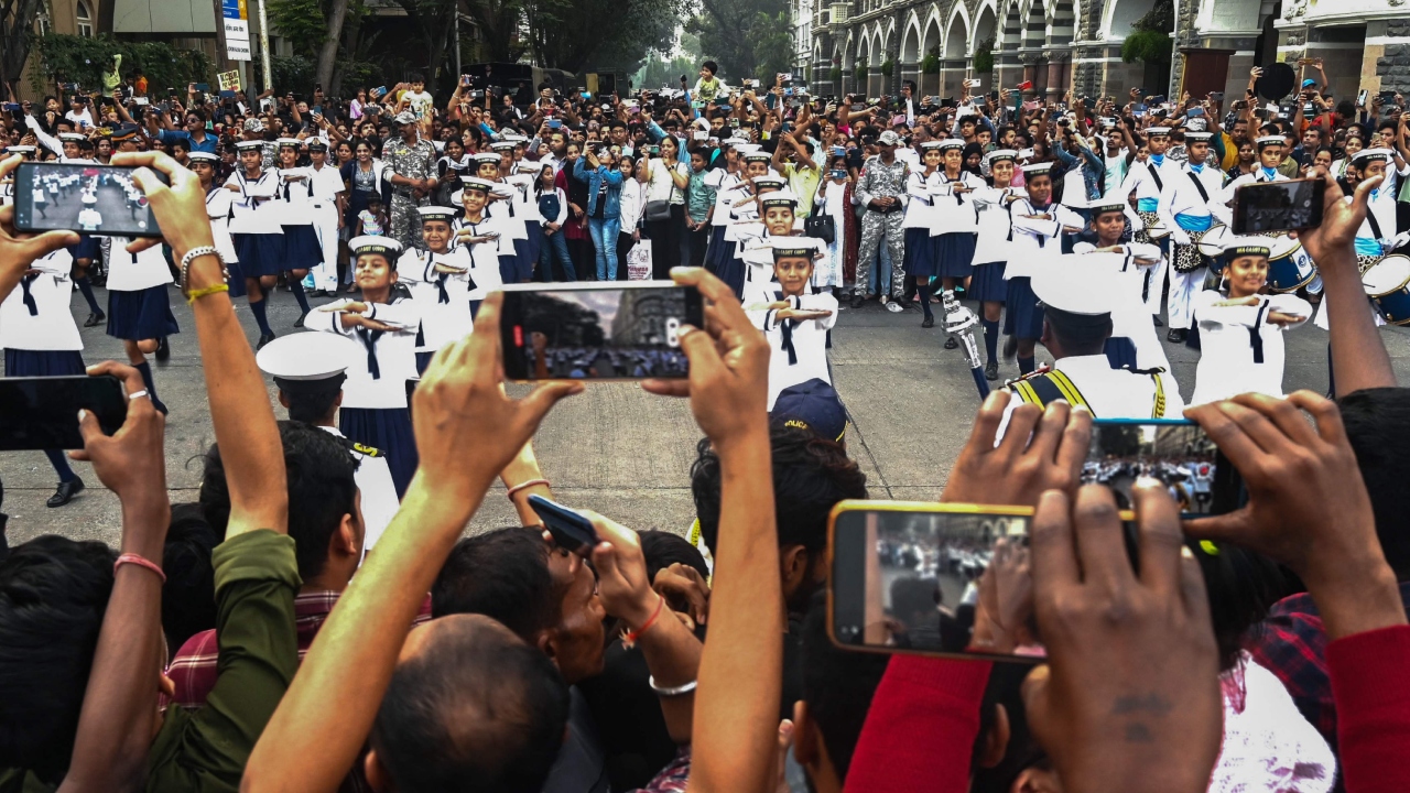 Spectators take photos of sea cadets performing during the Navy Day celebrations at the Gateway of India in Mumbai. Credit: AFP Photo