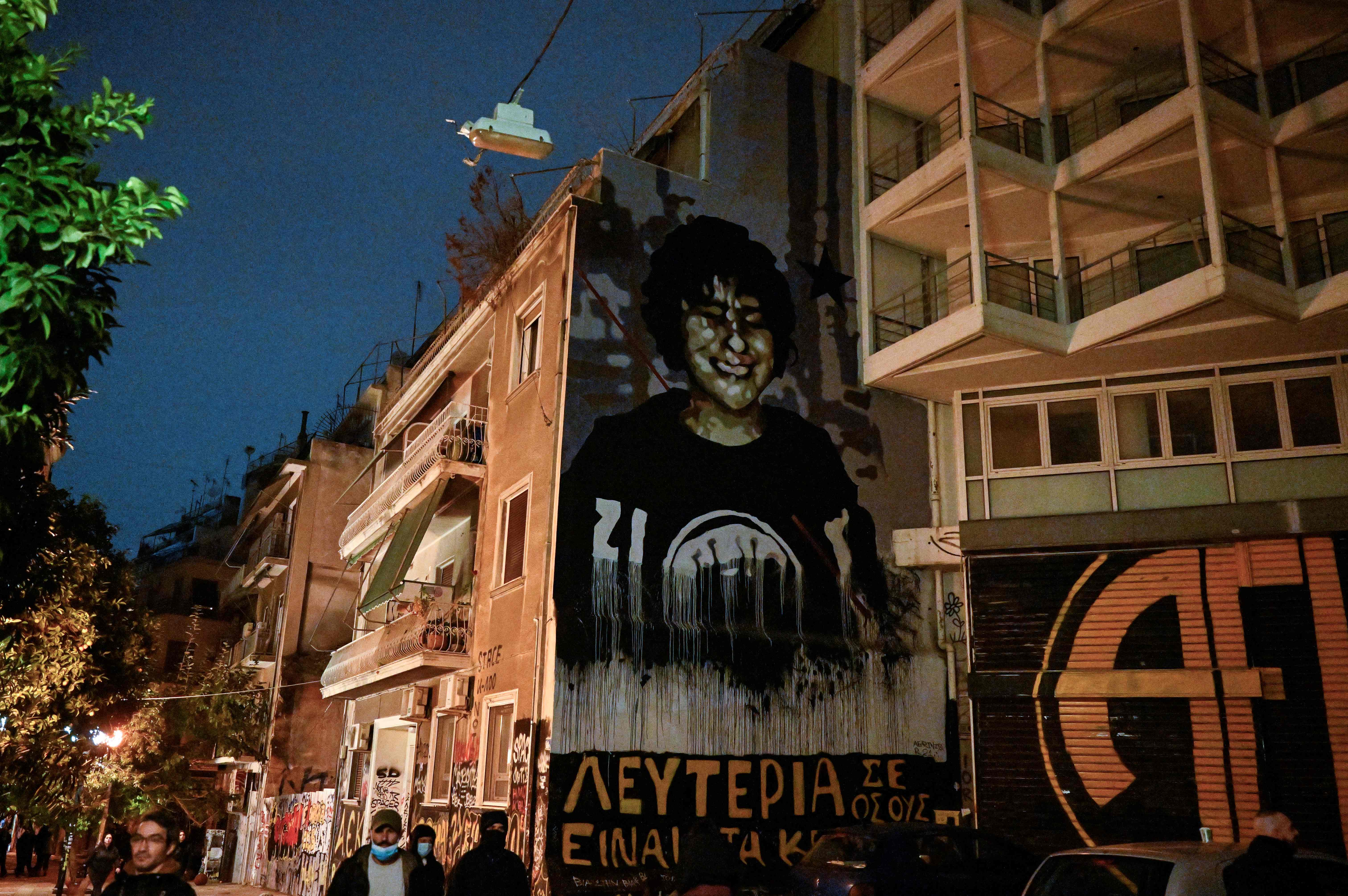 People walk by a mural depicting the 15-year old Alexis Grigoropoulos, killed by police, after a rally, marking the 14th anniversary of the 2008 fatal police shooting of a teenager in central Athens. Credit: AFP Photo