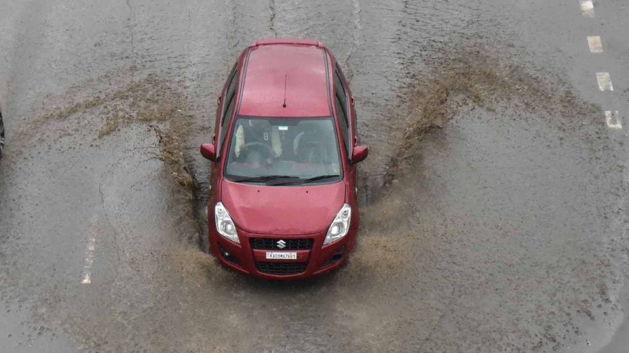 A car wades through a waterlogged street in Bengaluru. Credit: B K Janardhan/DH Photo