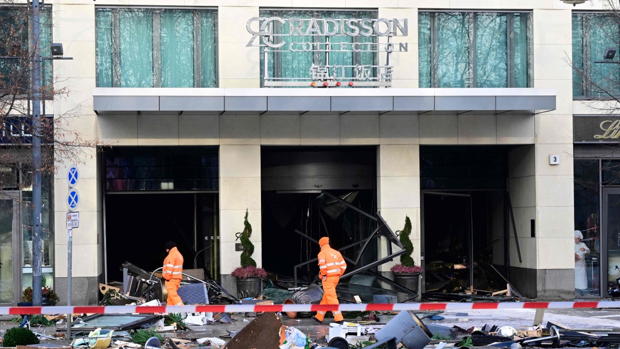 Workers of the city cleaning department walk past debris covering the street in front of the Radisson Blu hotel after a huge aquarium located in the hotel's lobby burst on December 16, 2022 in Berlin. Credit: AFP Photo