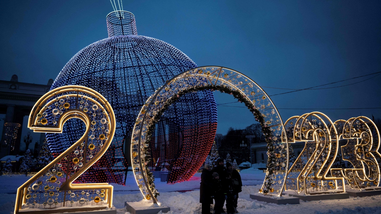 A family poses for a picture in front of Christmas and New Year decorations in Moscow on December 19, 2022. Credit: AFP Photo