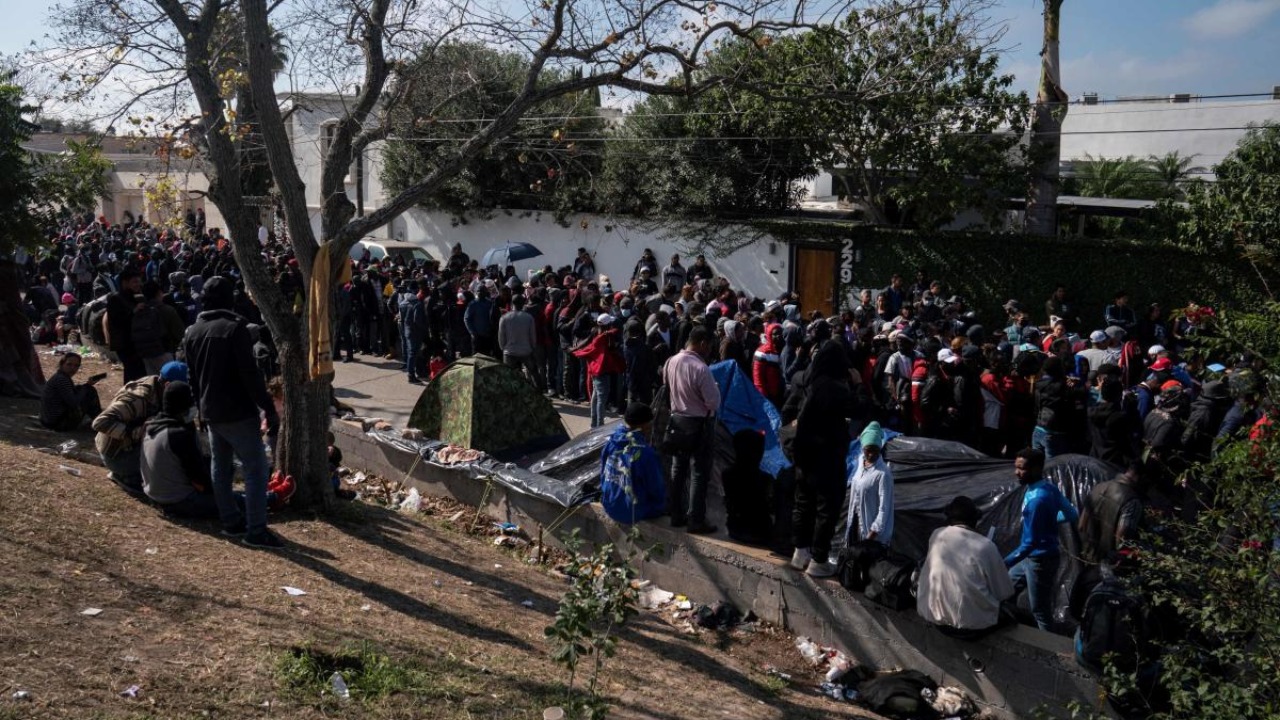 Asylum seekers wait in line to put their name on a list to get called when it is their turn to seek asylum in the US, the day after Title 42 had been expected to be lifted but now the decision has been postponed for December 27th, in Matamoros, Tamaulipas, Mexico. Credit: AFP Photo