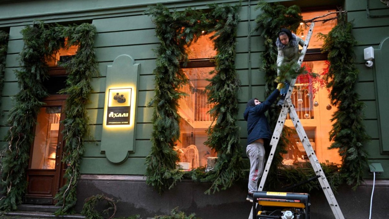 Employees decorate a window of a cafe which electricity comes from a power generator standing outside, in the centre of western Ukrainian city of Lviv during blackout hours amid Russian invasion of Ukraine. Credit: AFP Photo