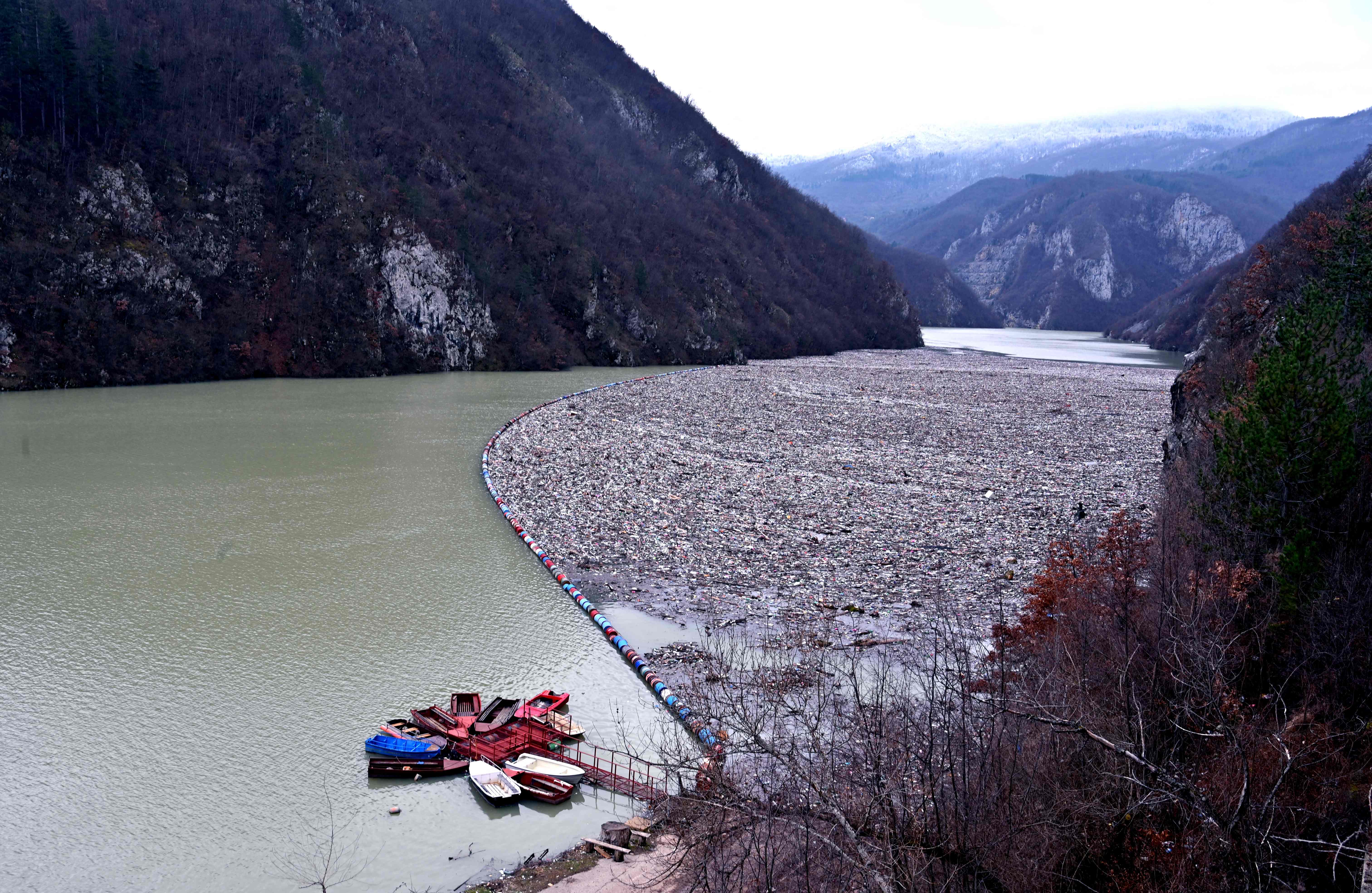 This photograph taken on January 26, 2023 shows waste and debris floating behind a primitive floating fender on the river Drina, near Visegrad, eastern Bosnia and Herzegovina. Credit: AFP Photo
