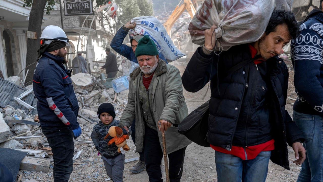 A Syrian man and his grandson walk in the debris in the Antakia historical city in Hatay after a 7.8-magnitude earthquake struck the country's south-east. Credit: AFP Photo