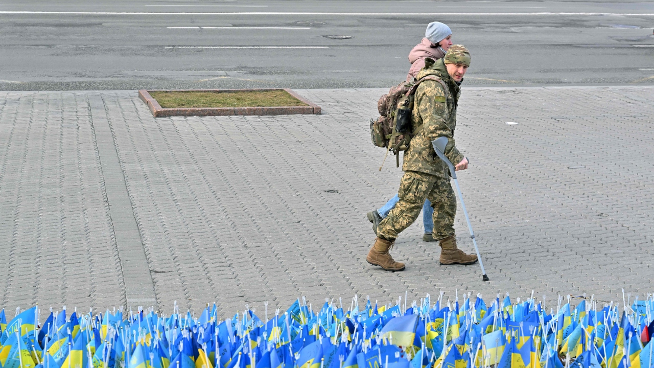 A wounded Ukrainian serviceman and his girlfriend walk past national flags each of which symbolizing the dead serviceman set at Independence Square in Kyiv on February 22, 2023, two days before the first anniversary of the Russian invasion to Ukraine. Credit: AFP Photo