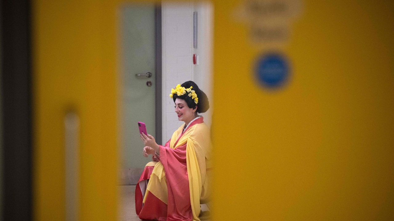 A member of Ukraine's Dnipro Opera, speaks on her phone backstage during the interval of a performance of Giacomo Puccini's opera Madama Butterfly in Scarborough Spa theatre in Scarborough, north-east England, on February 22, 2023. Credit: AFP Photo
