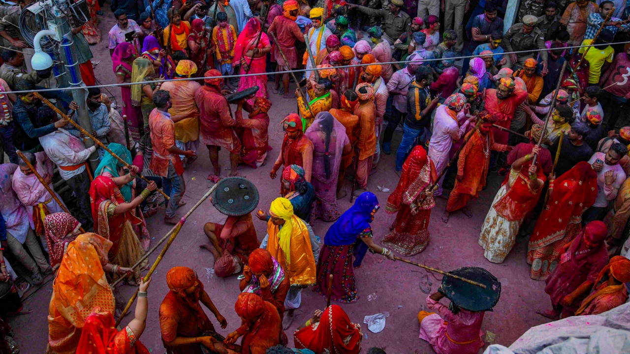 Holi in Barsana virtually is a repeat of Holi representing the 'Dwaapar' age with men trying to drench women with colours and women stopping them with baton attacks. Credit: PTI Photo