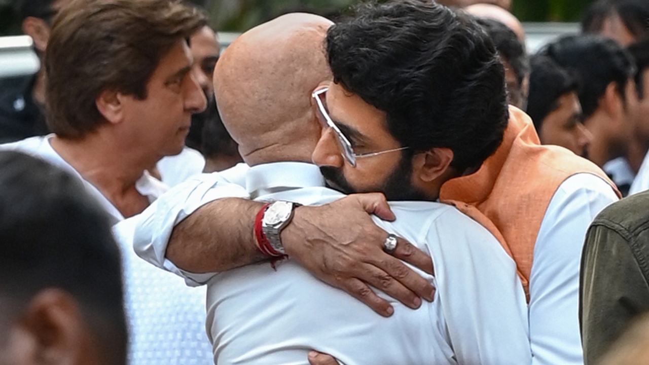Abhishek Bachchan hugs Anupam Kher during the funeral of Satish Kaushik in Mumbai. Credit: PTI Photo