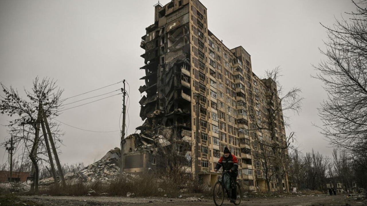 A man rides his bicycle in front of a destroyed apartment building after a Russian strike in the city of Avdiivka, Donetsk Oblast. Credit: AFP Photo