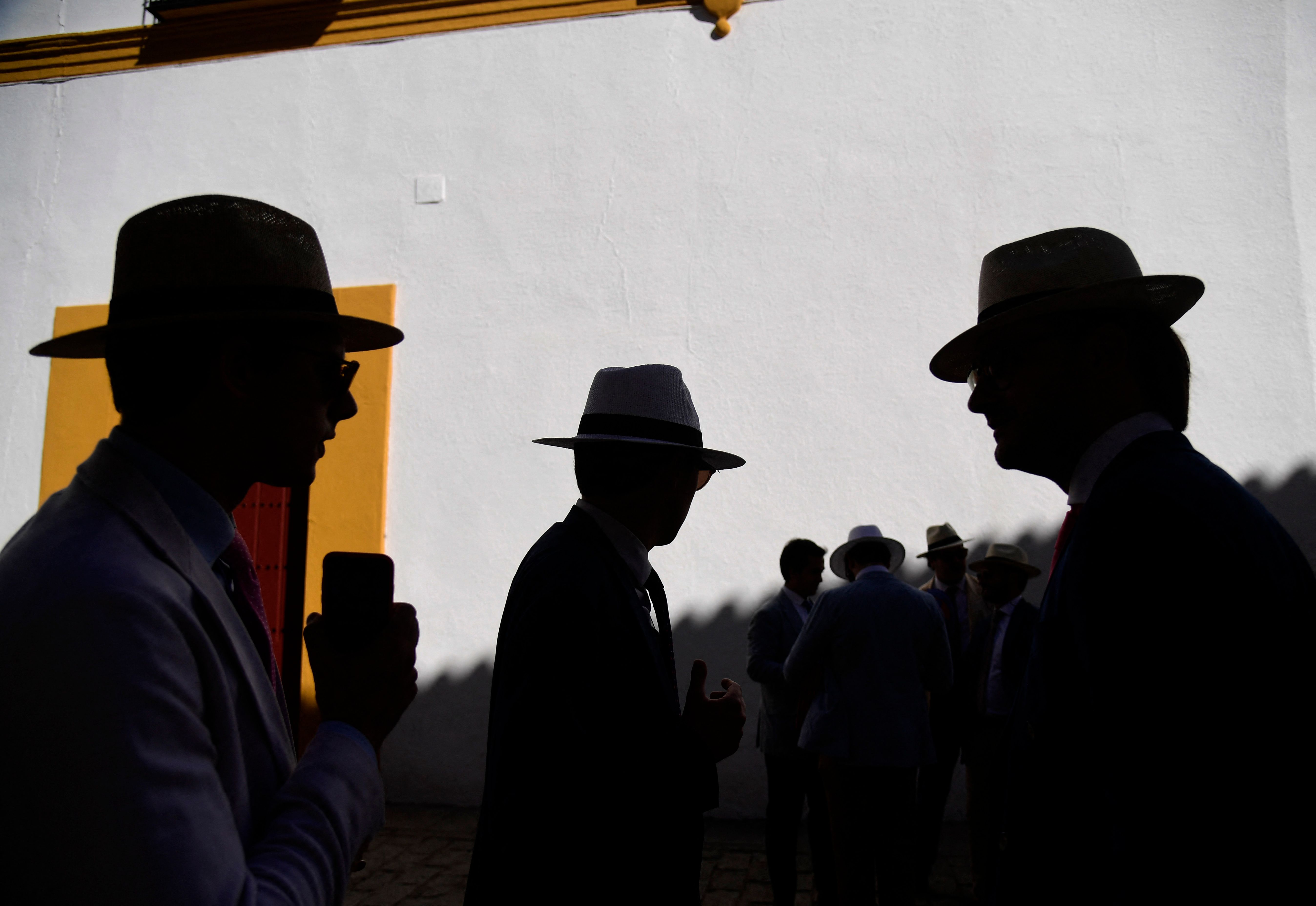 Silhouettes of men with hats in the shade at the entrance of La Maestranza bullring in Seville, as Spain is bracing for an early heat wave. Credit: AFP Photo