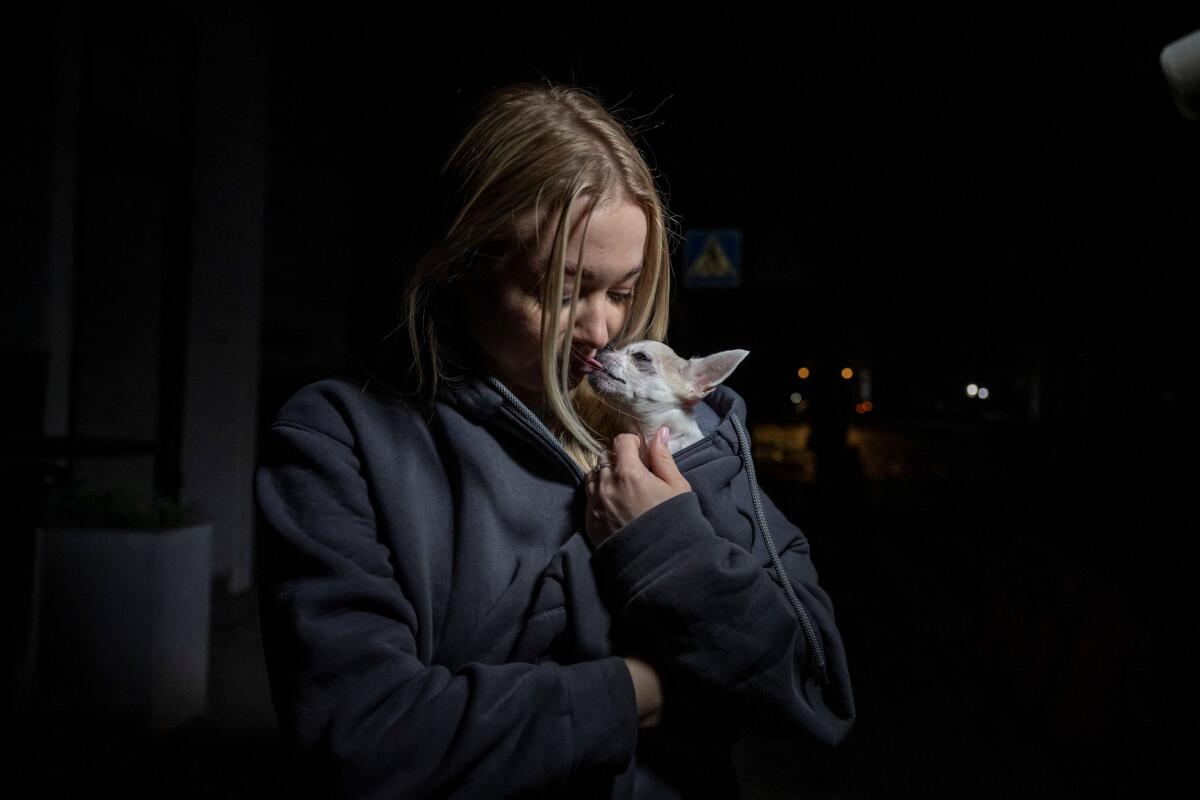 A local woman holds her dog at the site of a Russian missile strike, amid Russia's attack on Ukraine, in central Kharkiv. Credit: Reuters Photo