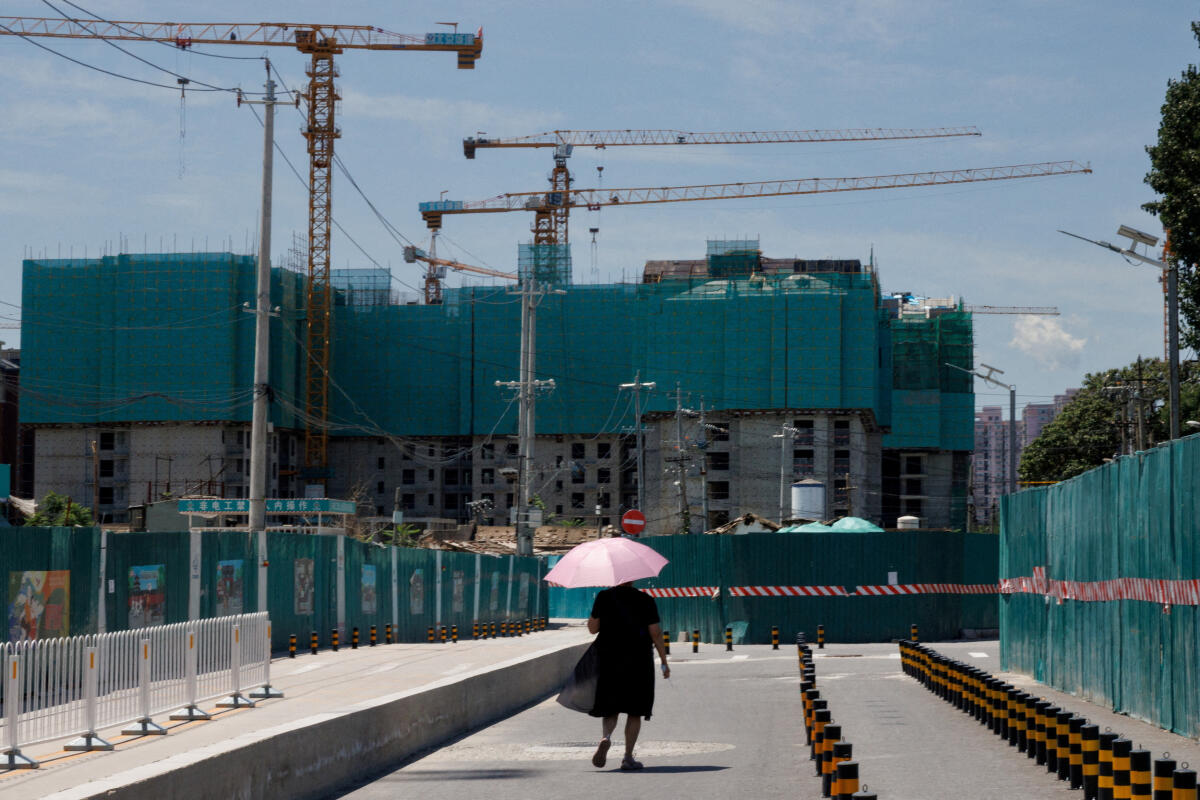 A woman walks near a construction site of apartment buildings in Beijing. Credit: Reuters Photo
