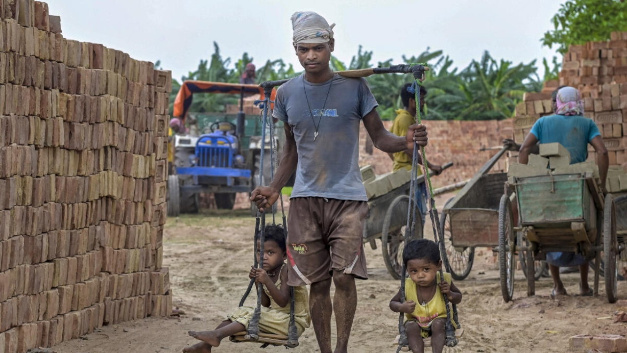 Nadia: A labourer with his children on Father’s Day while working at a brick kiln, in Nadia, Sunday, June 18, 2023. Credit: PTI Photo