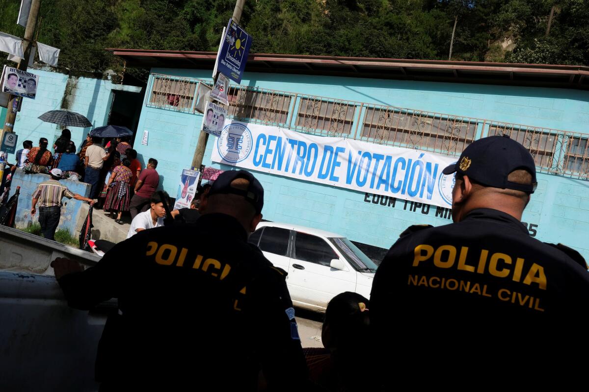 Police officers look on as people attend to cast their vote at a polling station during the first round of Guatemala's presidential election in Chinautla. Credit: Reuters Photo
