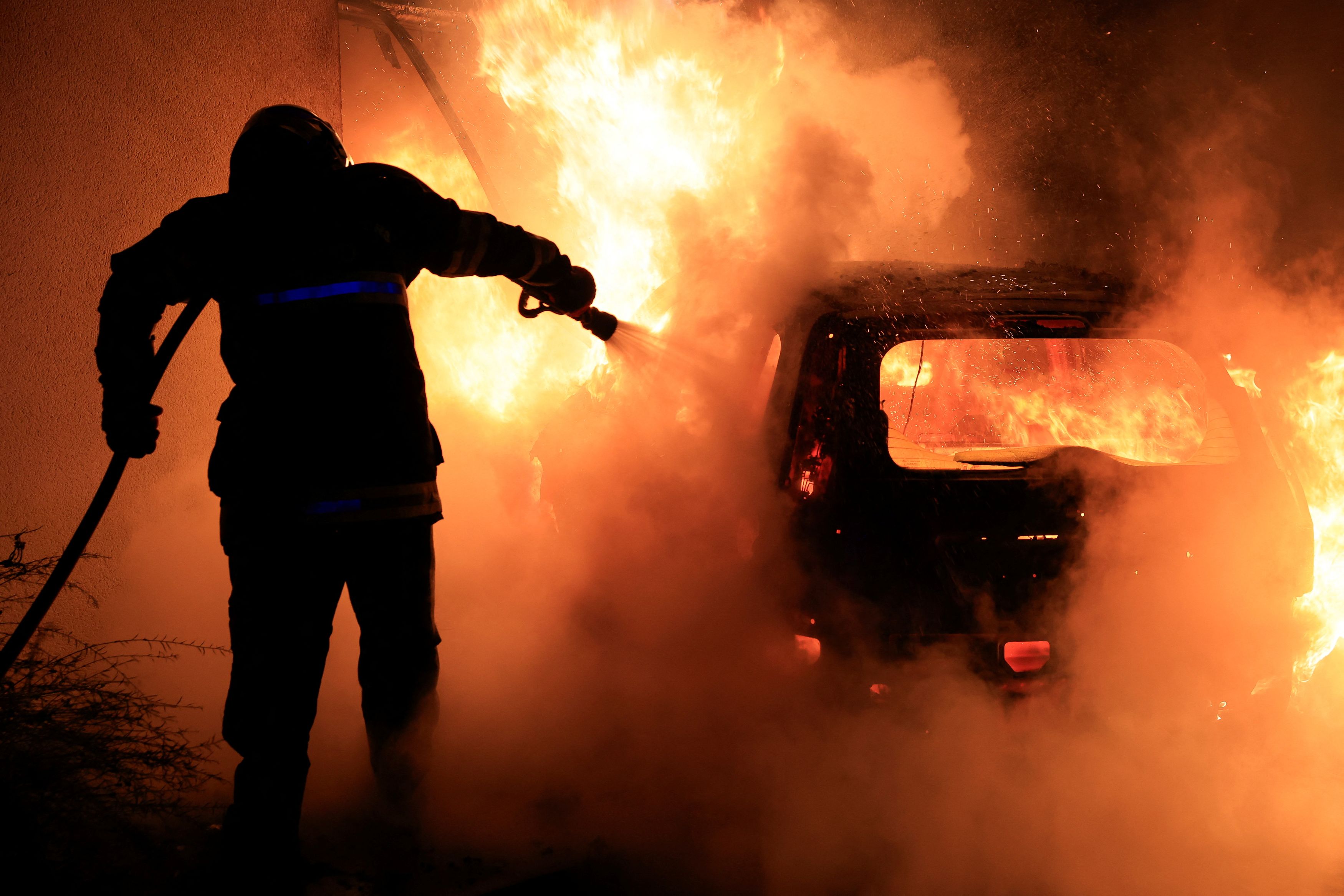 A French firefighter works to extinguish a burning car during the fifth day of protests following the death of Nahel, a 17-year-old teenager killed by a French police officer in Nanterre during a traffic stop, in Tourcoing, France. Credit: Reuters Photo