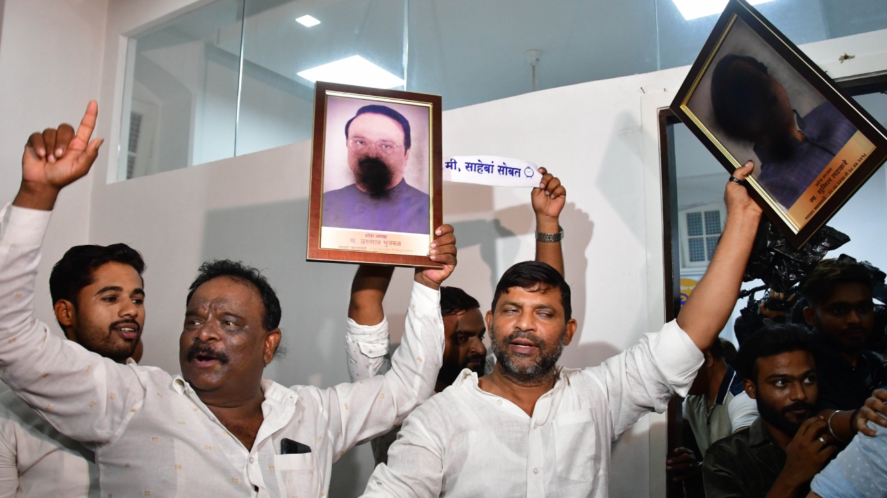Nationalist Congress Party (NCP) supporters holding portraits of party MLAs, who joined the Maharashtra government, after spraying black paint on their faces, shout slogans, at the NCP office, in Mumbai. Credit: PTI Photo