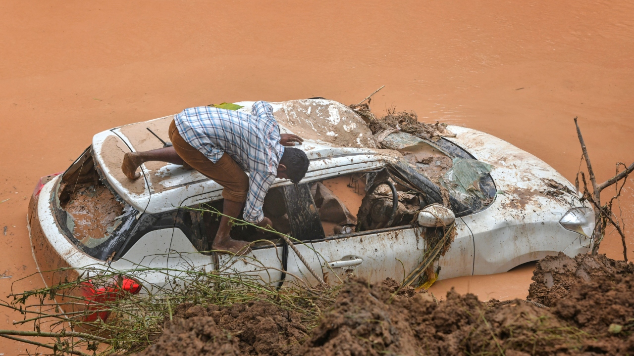 A man looks inside a car, that was washed away in floodwater, from which three bodies were found, at village Toga near Chandigarh. Credit: PTI Photo